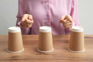 Woman playing shell game at wooden table, closeup
