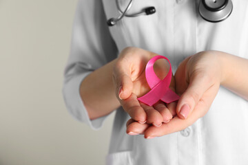 Mammologist with pink ribbon on light background, closeup. Breast cancer awareness