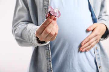Pregnant woman with pacifier on white background, closeup