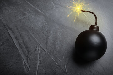Old fashioned black bomb with lit fuse on grey table, top view. Space for text