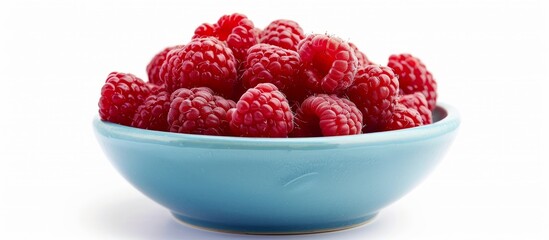 A bowl of boysenberries on a blue tableware, set against a white background. These natural fruits...