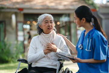 Compassionate Asian woman provides care to  elderly person in wheelchair outdoors. Engaging in physical therapy, happiness, encouraging positive environment for mature individuals with grey hair.