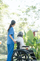Compassionate Asian woman provides care to  elderly person in wheelchair outdoors. Engaging in physical therapy, happiness, encouraging positive environment for mature individuals with grey hair. - obrazy, fototapety, plakaty