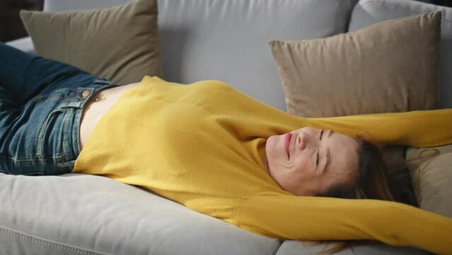 Closeup carefree woman falling on coach stretching at home. Girl romantic mood