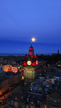 drone vertical shot of the Balmoral Clock Tower revealing a full moon and blue sky in the background