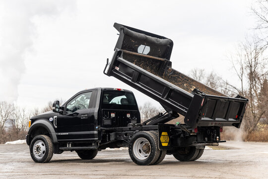 a black pickup truck with a dump truck bed and trailer