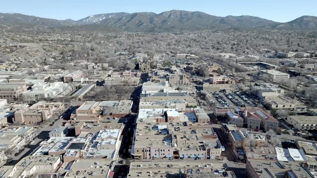 Downtown Santa Fe, New Mexico and mountains with drone video wide shot moving in a circle.