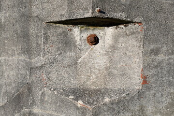Concrete bunker corner with rusty iron hardware.