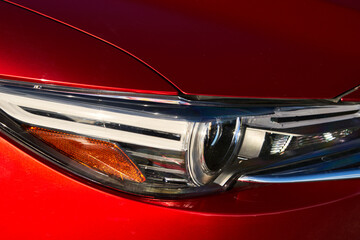 Closeup of the chrome headlights on a brilliant red colored car.