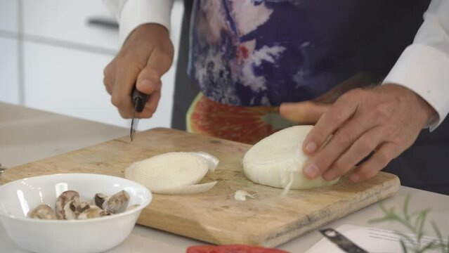 Slicing a big white onion and adding pieces to food processor to make a raw vegan burger recipe