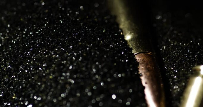 Gunpowder detail macro shot with .300 AAC Blackout bullets falling, pan