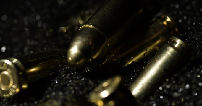 Macro detail shot of 9&times;19mm Parabellum bullets in slow motion falling on gunpowder