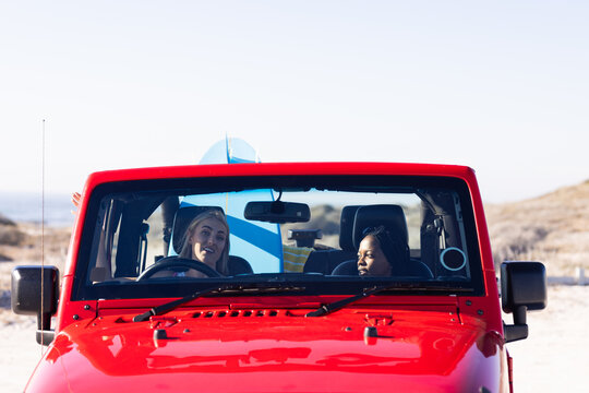 Young African American woman and young Caucasian woman enjoy a road trip in a red jeep on a road tri