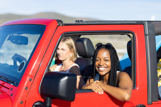 Young African American woman and young Caucasian woman enjoy a sunny drive on a road trip