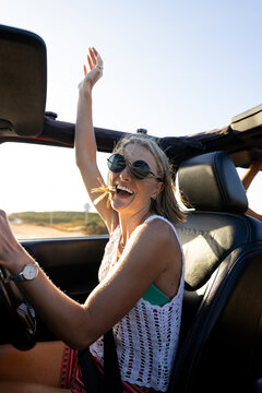 Young Caucasian woman enjoys a sunny drive in a convertible on a road trip