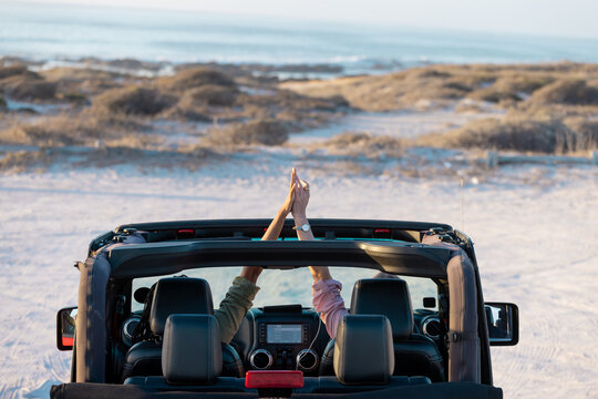 Two people enjoy a scenic drive by the beach on a road trip
