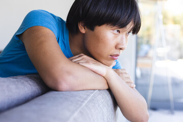 Teenage Asian boy looks sad and contemplative at home, with copy space