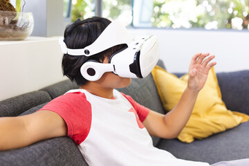 Teenage Asian boy explores virtual reality at home, with copy space