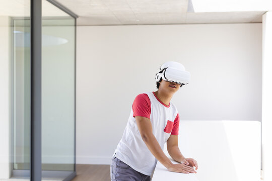 Teenage Asian boy explores virtual reality at home, with copy space