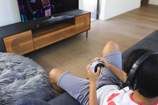Teenage Asian boy enjoys gaming at home, with copy space