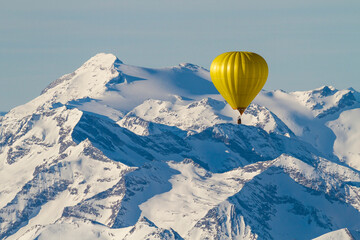 Yellow balloon flying over snow-covered mountains