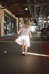 Young caucasian girl runs through outdoor market on summer day