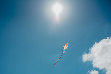 colourful kite in the sky with fluffy clouds and blue sky