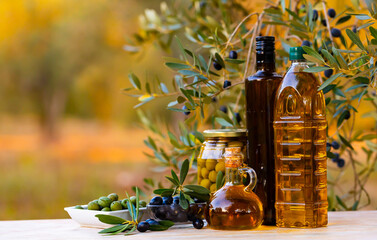 Decanter and various bottles of fragrant olive oil on the table with olive branches and fresh olives
