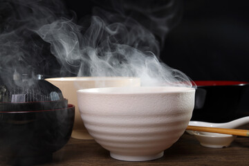 Smoke vape fog rising flowing out of miso soup black red white bowl on dark black background - 736747691