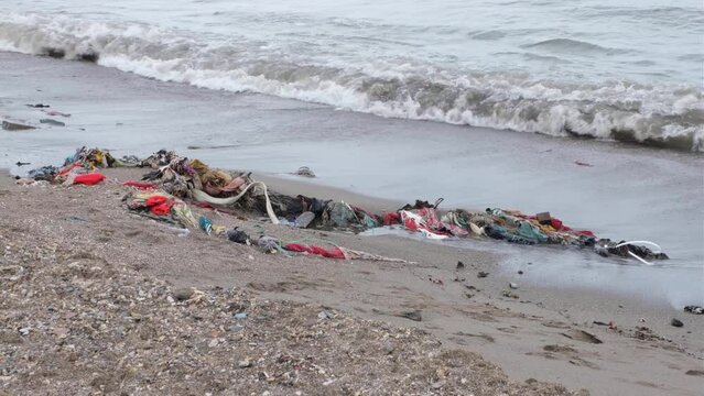 Discarded clothes and fabric rubbish, resulting from fast fashion, polluting the beach in tropical island destination in Southeast Asia