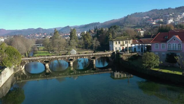 Calm water in River Vez reflects symmetrical arches under bridge in town of Arcos de Valdevez in Portugal