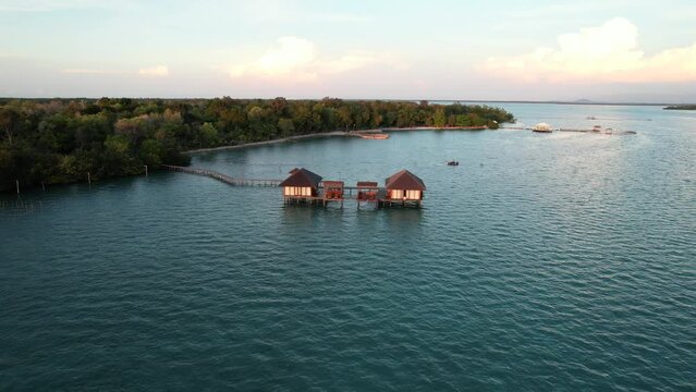 Long Wooden Pier Leading to Two Over Water Bungalows Resort At Sunset at Leebong Island, Belitung Indonesia - Aerial Parallax