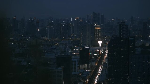 Bangkok night skyline with busy road and blurry bush foreground