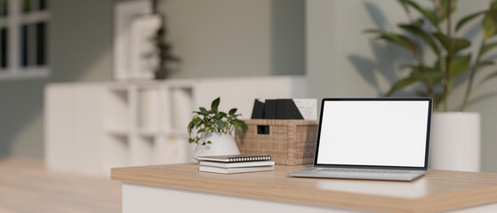 A laptop white-screen mockup and decor on a minimal wooden table in a modern and bright room.