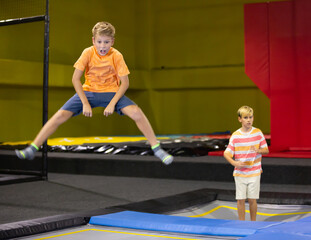 Playful boy jumping on trampoline at playground indoor