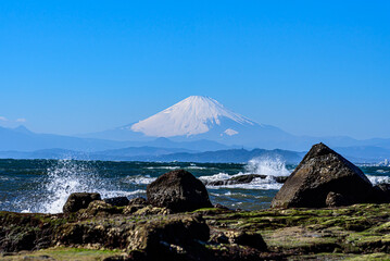 波飛沫が上がる江の島岩場から臨む富士山
