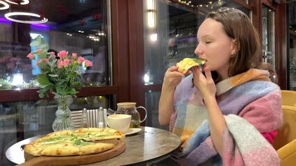 Caucasian woman eats pide holding a piece in her hand and bites off with her teeth while sitting in a street restaurant. slow motion. High quality 4k footage