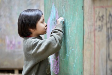 集中して壁に絵を描く男の子 / A boy concentrating on painting on the wall