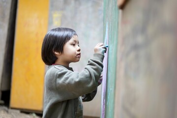 集中して壁に絵を描く男の子 / A boy concentrating on painting on the wall