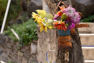 Cenotafio popular mexicano en un tronco de un arbol con flores de tela