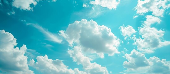 The azure sky with fluffy cumulus clouds creates a stunning natural landscape, resembling a piece of art. The electric blue hue of the sky is a mesmerizing meteorological phenomenon