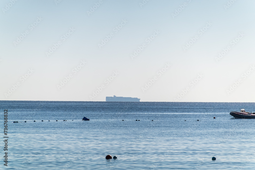 Wall mural Calm blue sea with the silhouette of a large ship on the horizon