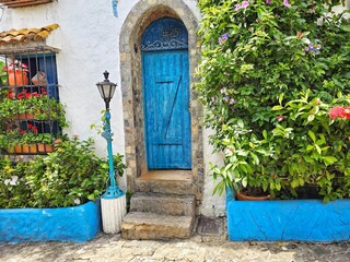 blue arched door with lantern and green garden and a small ladder for access to the white house