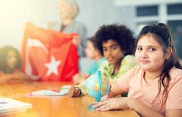 Ten-year-old schoolgirl studying the history of Turkey in lesson and attentively looking for her on the globe