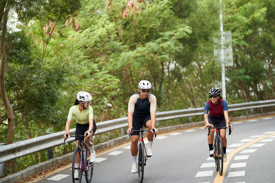 young asian people riding bicycle outdoors on rural road