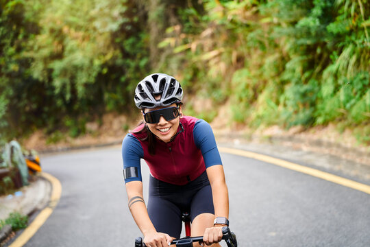 young asian woman riding bike outdoors on rural road