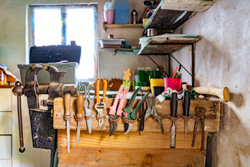 Various tools: file, screwdriver, hammer, pliers, garden tools are displayed on wooden shelf inside...