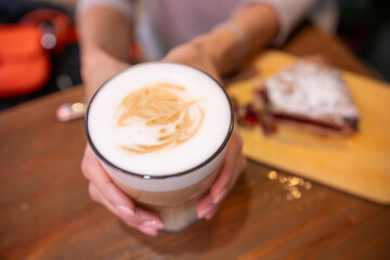 woman hands with latte on a wood table in cafe