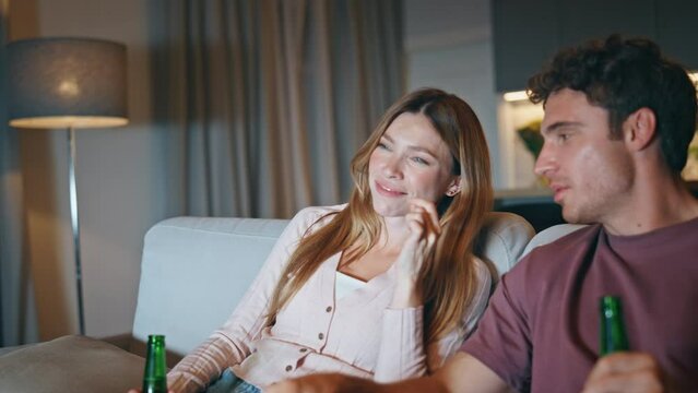 Laughing couple watching sitcom sitting at night closeup. Lovers eating snacks