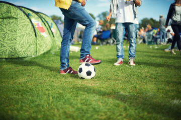 Man, feet and playing with soccer ball outside of his tent group of colourful camping. Row of marquees placed on ground at musical concert, entertainment event and carnival celebration sporty party